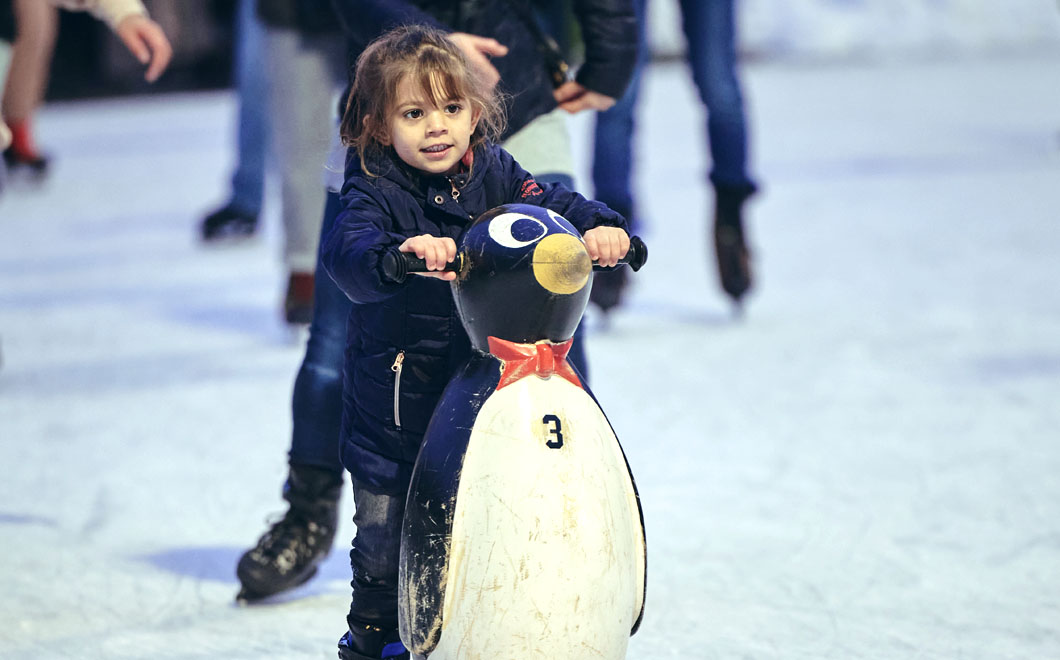 Mädchen auf dem Eis mit Pinguin