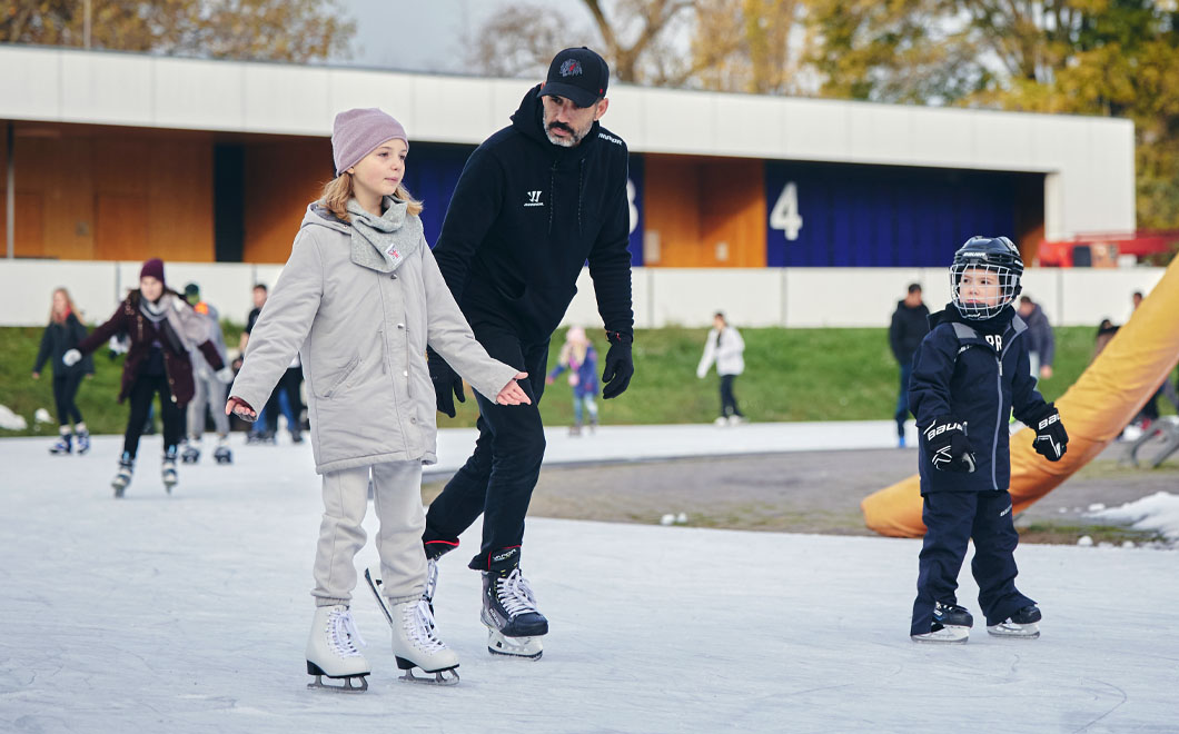 Mann mit 2 Kindern auf dem Aussenring der Eissporthalle