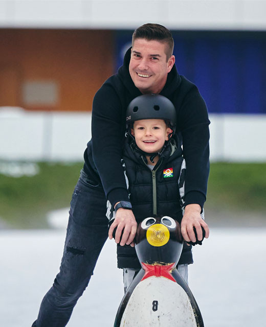 Mann und Kind mit Eisgleiter auf dem Eis