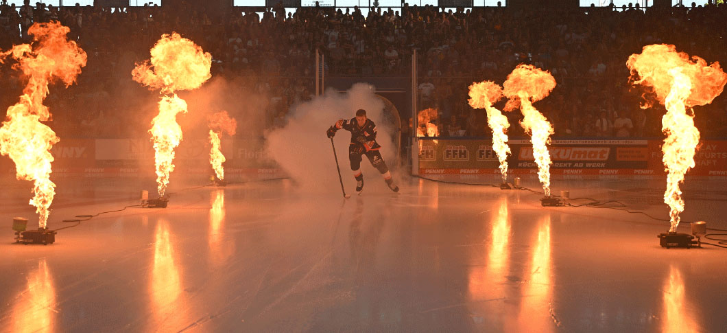 Eishockeyspieler auf dem Eis mit Pyroeffekten rechts und links